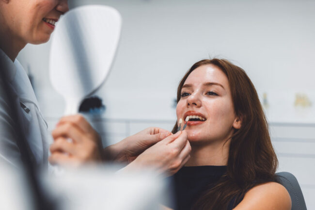 A woman sits in a dental chair as a dentist cleans her teeth, showcasing a bright and professional dental office.