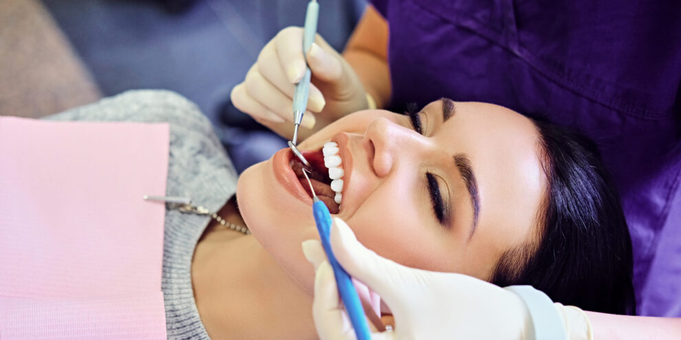 Woman smiling during a dental checkup, receiving treatment to help prevent bad breath.