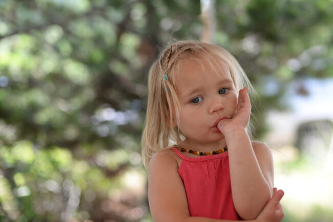 Thumb Sucking behavior in a toddler sucking her thumb outdoors, illustrating common childhood oral habits.
