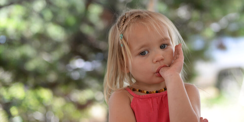 Thumb Sucking behavior in a toddler sucking her thumb outdoors, illustrating common childhood oral habits.